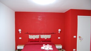A red-themed bedroom with a bed, bedside tables, and a door. - Sorrento deluxe Balcony (Sorrento)