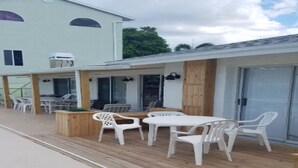 Une terrasse extérieure avec une plateforme en bois, des chaises en plastique blanches et une table.