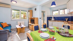 Ett kompakt bostadsutrymme med en matplats, ett litet kök och en liten sittgrupp.