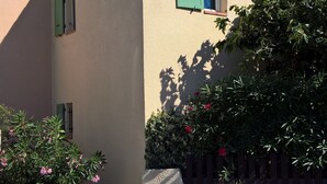 Un bâtiment à l’extérieur beige, avec une petite fenêtre dotée de volets verts et une antenne visible.