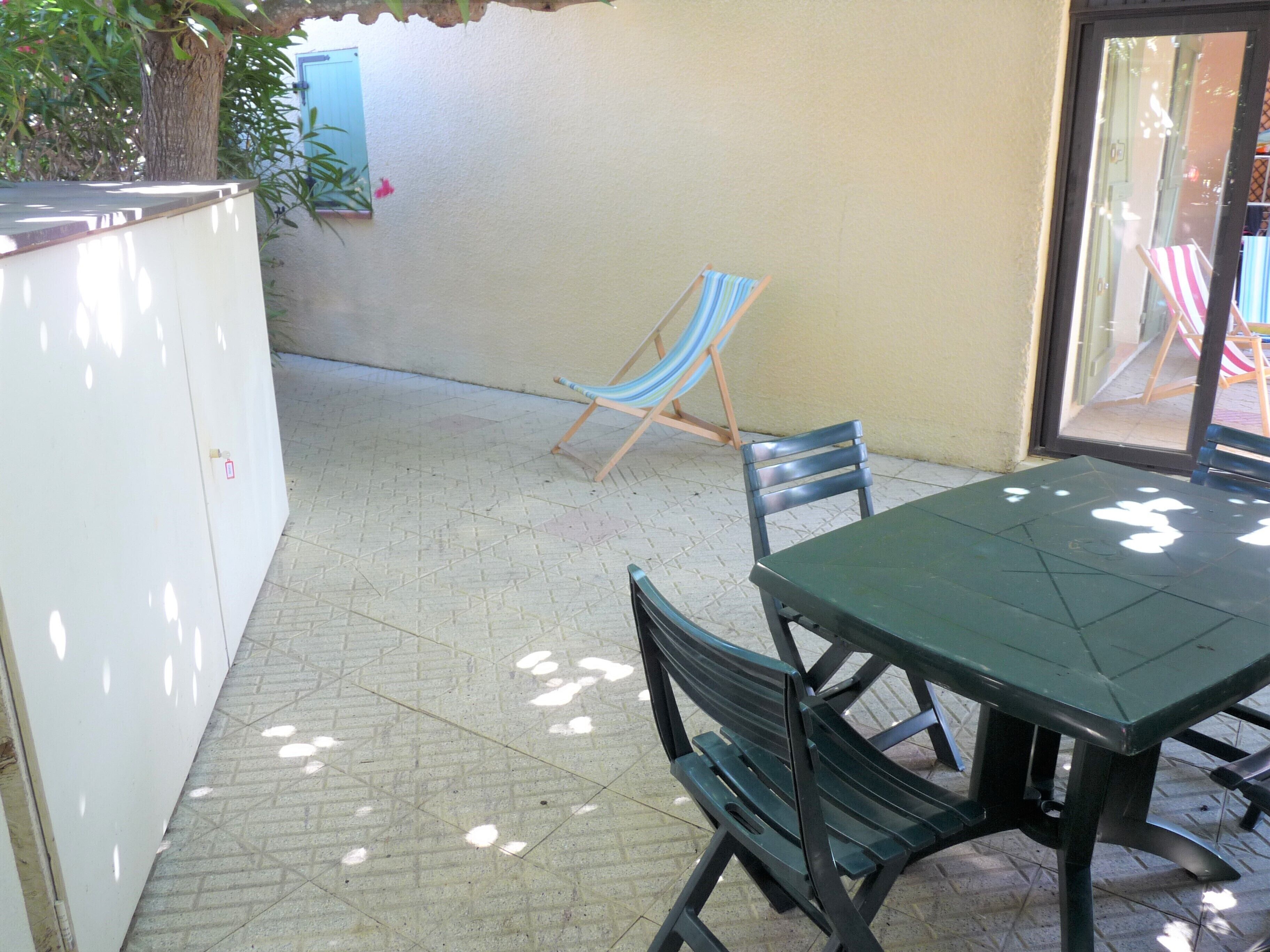 A patio with a table and chairs, a hammock, and a view of the street.