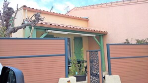 Une maison avec une porte verte, un porche abrité et une cour arrière clôturée.