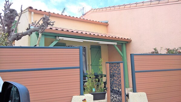 A house with a green door, a covered porch, and a fenced backyard.
