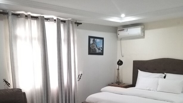 A modern hotel room with a large bed, a sofa, a coffee table, and a picture on the wall. - Mitos Luxury Suites (Lagos)