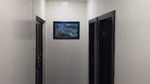A narrow hallway with a marble floor, white walls, and a framed picture on the wall. - Mitos Luxury Suites (Lagos)