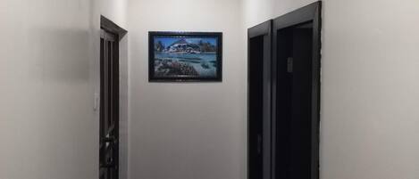 A narrow hallway with a marble floor, white walls, and a framed picture on the wall.