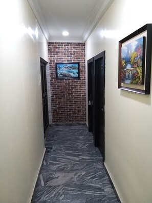Un pasillo con pared de ladrillo, un cuadro enmarcado y una puerta.