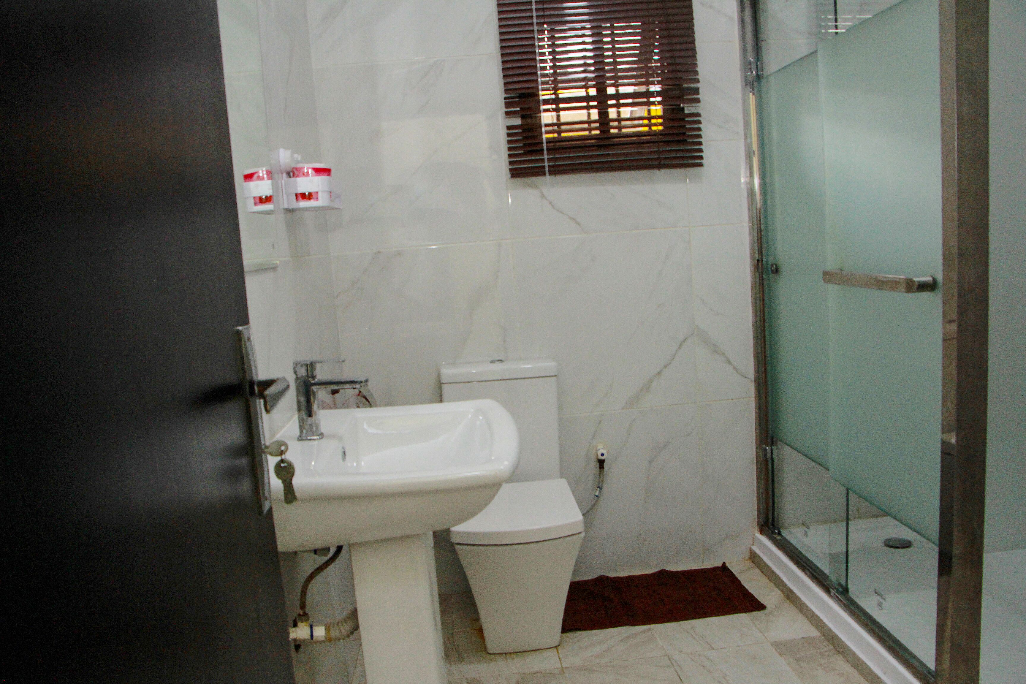 A bathroom with a white sink, toilet, and glass shower enclosure.
