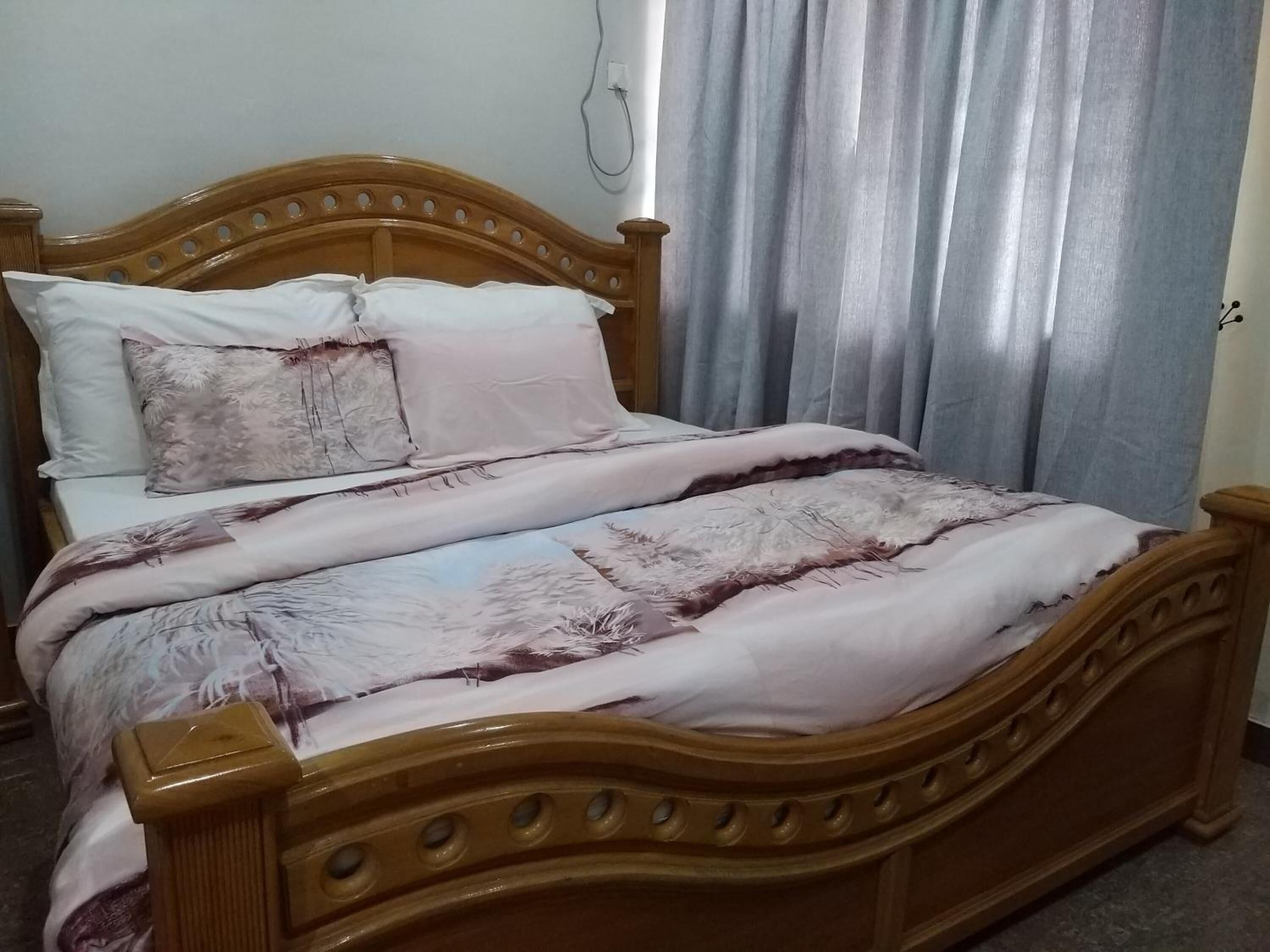 A wooden bed with a headboard, white pillows, and a patterned bedspread.