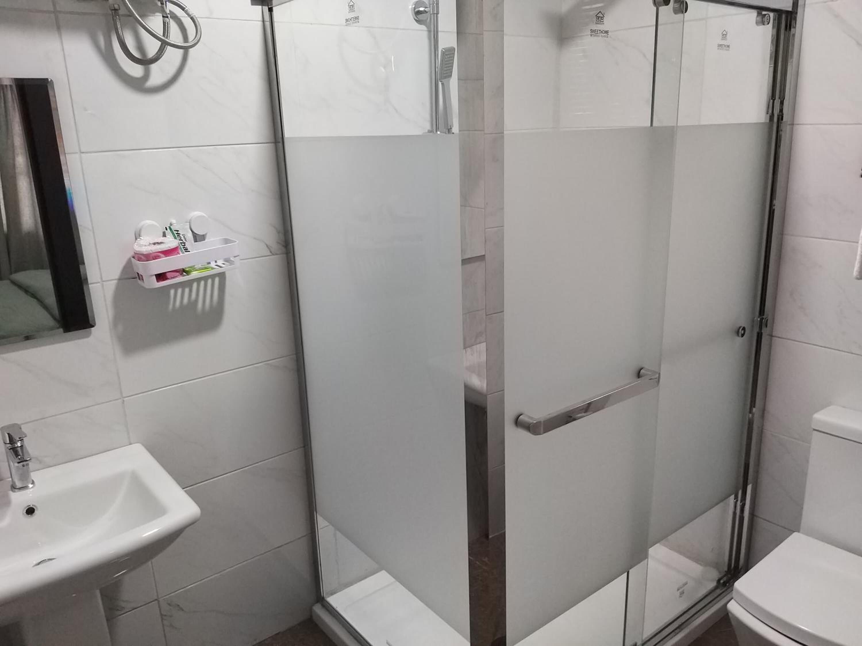 A bathroom with a glass-enclosed shower, a sink, and a toilet.