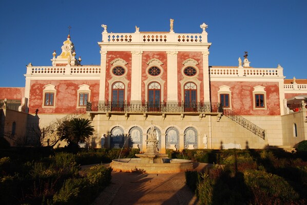 A historic building with a central courtyard, a fountain, and a staircase leading to the entrance.