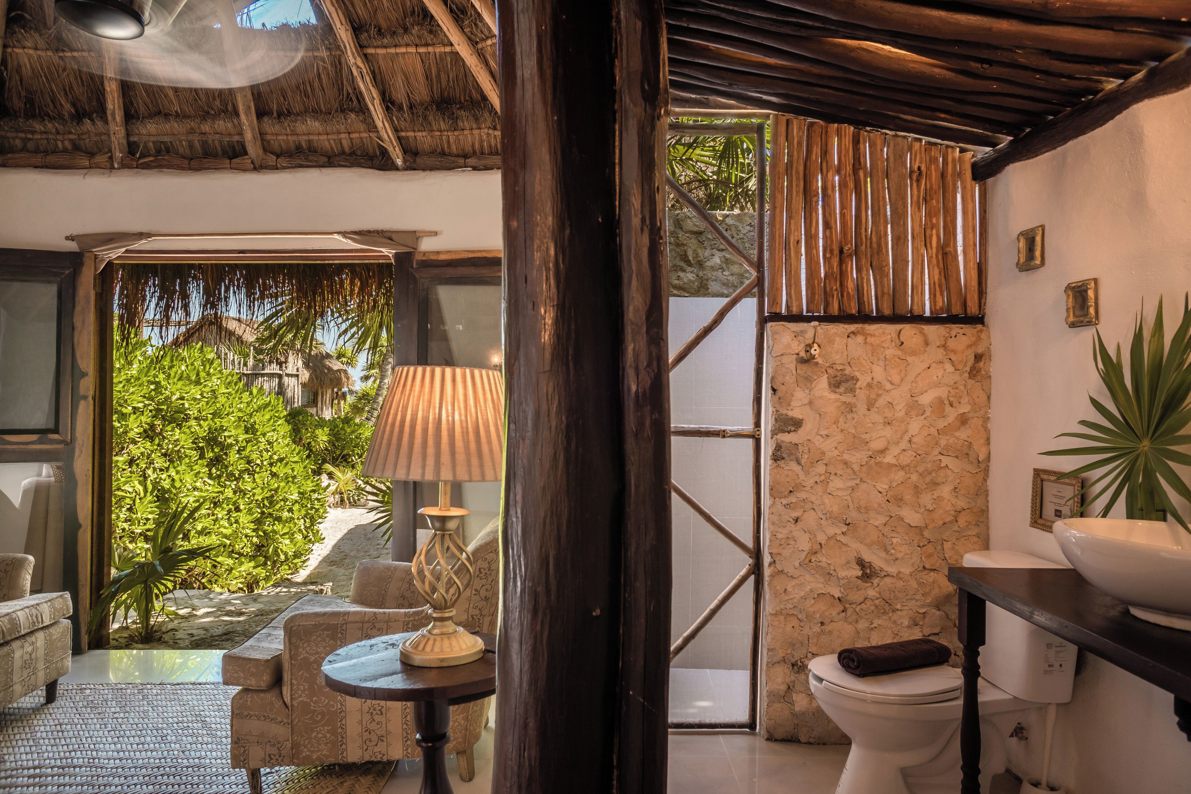 A bathroom with a stone wall, a white toilet, a sink, and a towel on the toilet.