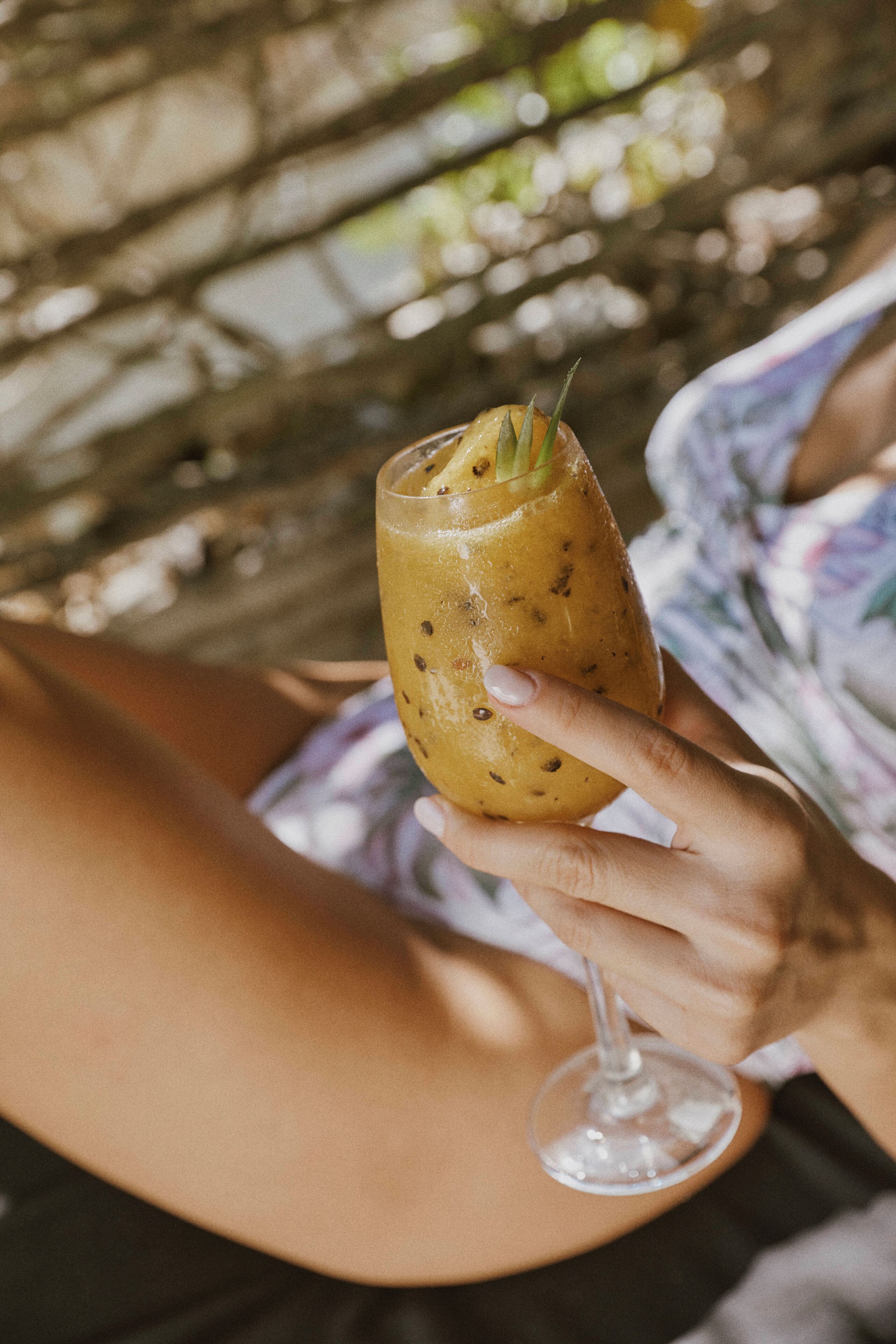 A person holding a drink with a garnish, wearing a patterned garment.