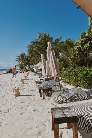 Un resort frente al mar con sillas de descanso, sombrillas y un paseo marítimo de arena.