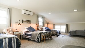 Un dormitorio acogedor con dos camas, un escritorio y una silla. Hay una ventana con cortinas, un ventilador de techo y un aire acondicionado.