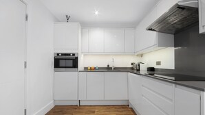 A modern kitchen with white cabinetry, a black oven, and a stainless steel range hood. - Hermitage Rd N4 🚇 Manor House | Ground floor (London)