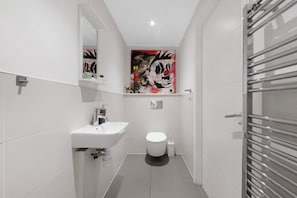Une salle de bain moderne avec un lavabo blanc, des toilettes et un grand miroir.