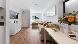 A modern, well-lit living area with a sofa, coffee table, and a vase with flowers. - Hermitage Rd N4 🚇 Manor House | Ground floor (London)