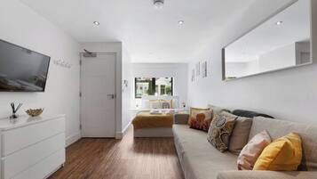 Quarto moderno com cama, sofá, televisão e guarda-roupa branco.