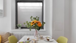 A dining table with a vase of flowers, plates with food, and a window with blinds. - Hermitage Rd N4 🚇 Manor House | Ground floor (London)