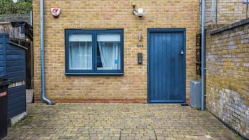 A brick building with a blue door and a window with curtains.