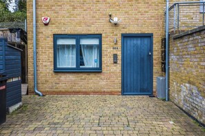 A brick building with a blue door and a window with curtains. - Hermitage Rd N4, Manor House | Ground floor (London)