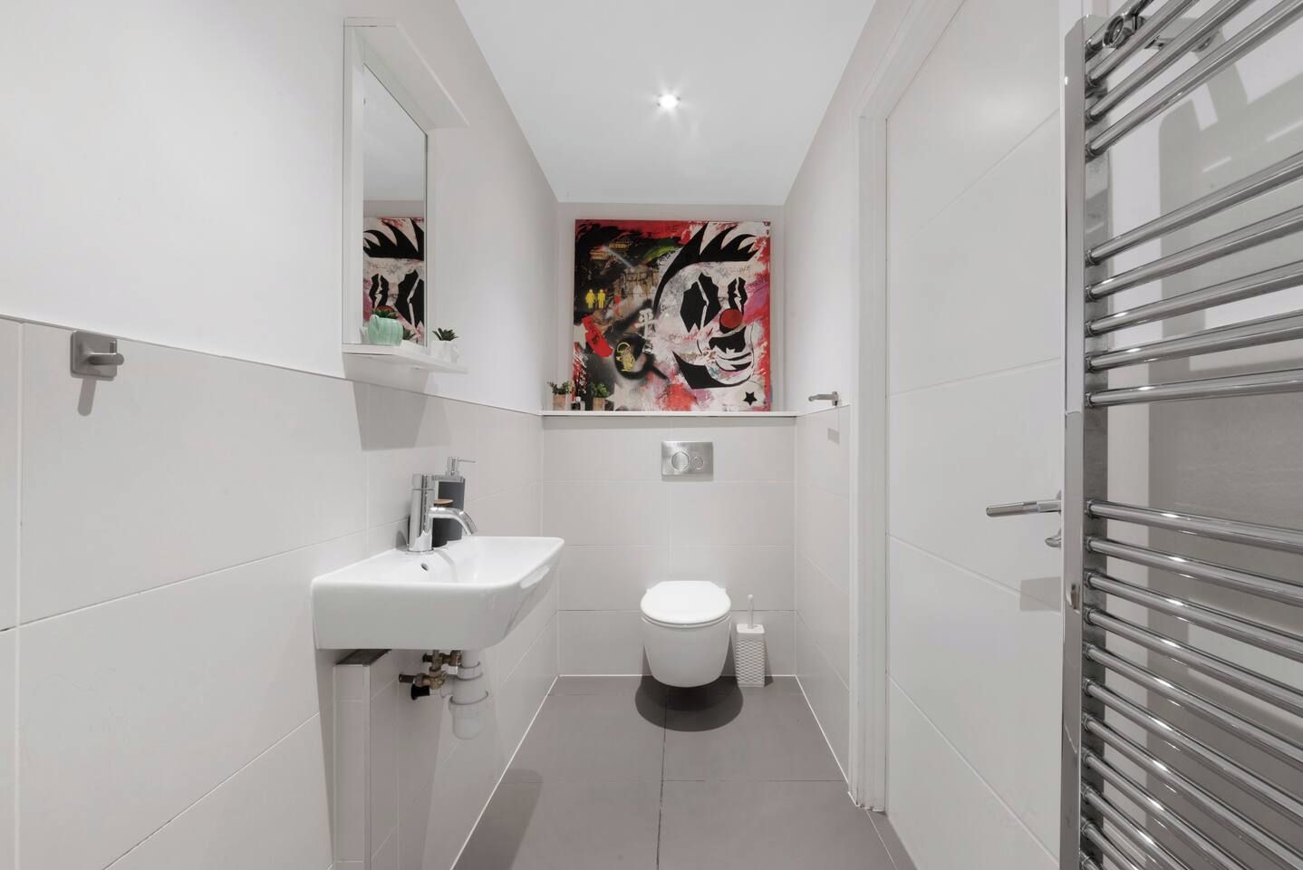 A modern bathroom with a white sink, toilet, and a shower area with a glass door.