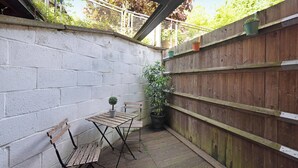 Eine Terrassenfläche mit Tisch und Stühlen, einem Blumentopf und einem Holzzaun.