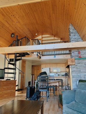 A spacious loft with a wooden interior, a kitchen area, and a dining space. - Eagle's Landings Lakeside Cabin (Lakeside)