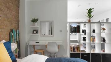 A modern bedroom with a bed, a desk, a chair, a bookshelf, and a mirror.