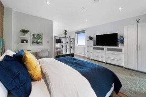 A modern bedroom with a bed, a TV, a bookshelf, and a desk.