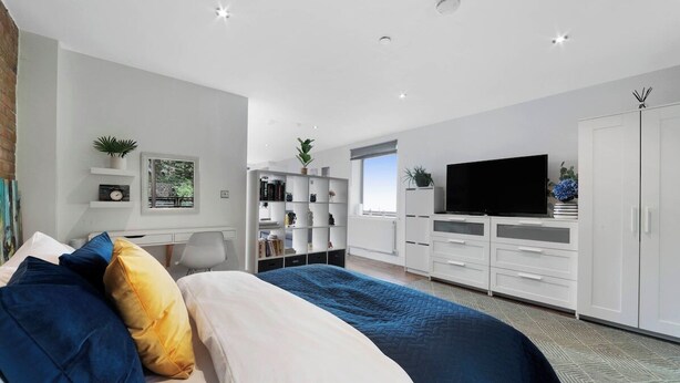 Een moderne slaapkamer met een groot bed, een televisie en ingebouwde opbergruimte.