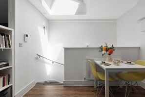 Une pièce moderne avec une lucarne, une table à manger avec des chaises, un radiateur et une bibliothèque.