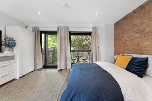 A bedroom with a bed, a dresser, a TV, and a balcony with a table and chairs.