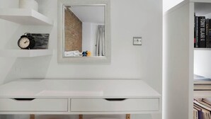 Een moderne badkamer met een witte wastafel, een spiegel, een potplant, een klok en een boekenplank.