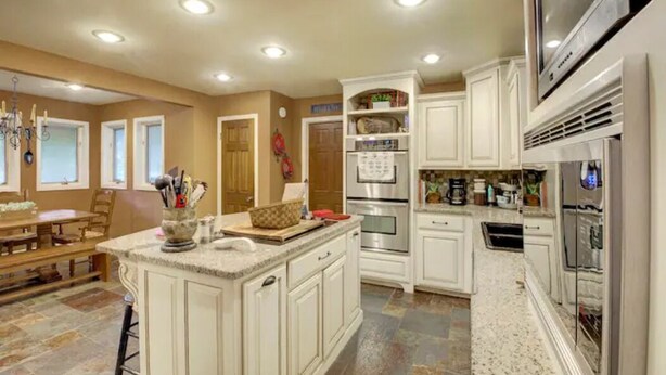 A spacious kitchen with white cabinetry, a central island, and built-in appliances. - Entire Spacious 4BR Home - close to downtown & minutes to trails! (Bentonville)