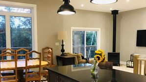 A modern kitchen with a central island, pendant lights, and a dining area with wooden chairs and a table.