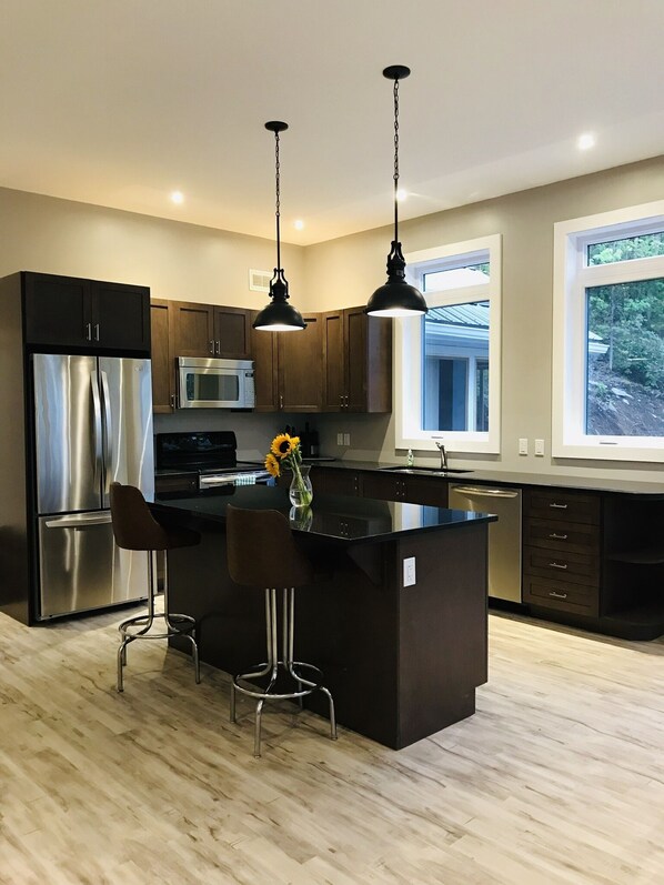 A modern kitchen with a central island, stainless steel appliances, and pendant lighting.