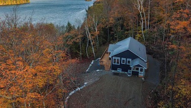 A house surrounded by autumn foliage and a lake.