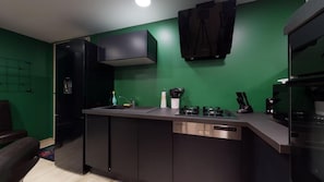 Una cocina moderna con una pared verde, armarios negros y electrodomésticos de acero inoxidable.