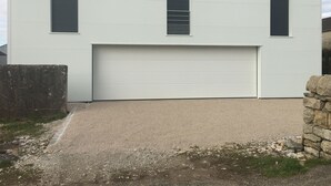 Ein modernes Gebäude mit flachem Dach, einer großen Garagentür und zwei Fensterläden.