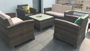Ein Balkon mit Korbmöbeln, darunter zwei Sofas und ein kleiner Tisch.