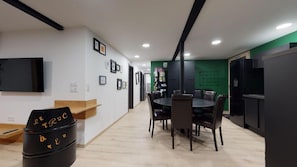 Una cocina moderna con comedor, piso de madera y un cubo de basura negro con texto amarillo.