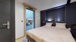 Ein Schlafzimmer mit Bett, Tür und Blick ins Freie.