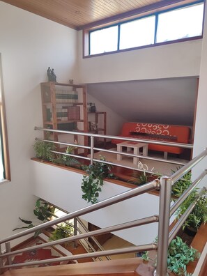 A multi-level interior with a staircase, a red sofa, and a bookshelf.