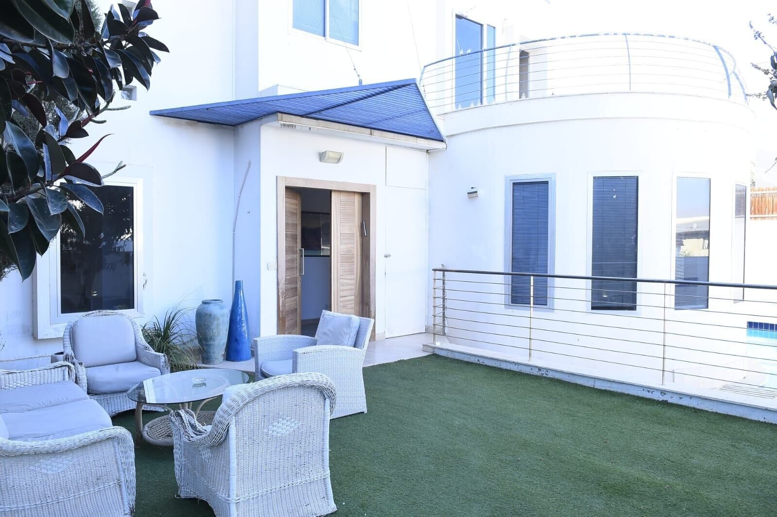 A modern outdoor patio with wicker furniture, a small table, and a blue vase.