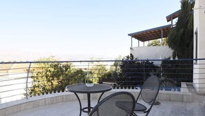 A rooftop terrace with a round table and two chairs, surrounded by a metal railing. - Casa de la familia (Eilat)