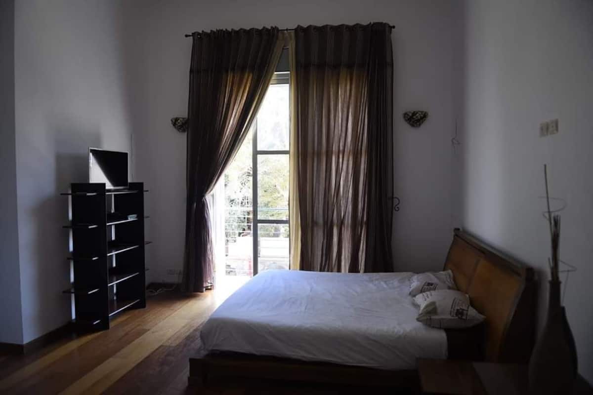 Een slaapkamer met een bed, een kledingkast en een raam met gordijnen.