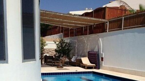 A swimming pool with a Star of David design, surrounded by a white wall and a wooden fence. - Casa de la familia (Eilat)