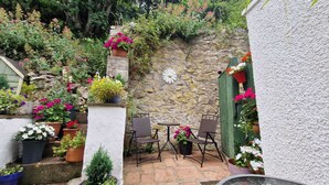 Une terrasse avec un mur en pierre, des plantes en pot et du mobilier d’extérieur.